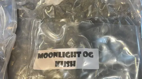 Vacuum-sealed pack of cannabis with label saying "Moonlight OG Kush" - a type of strain usually grown in California.
