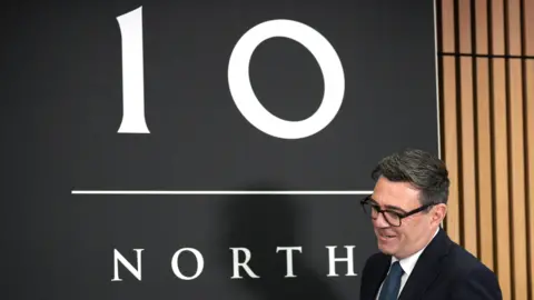 Andy Burnham next to a sign saying 10 North.