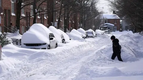 A resident walks through deep snow piles in Toronto, Canada