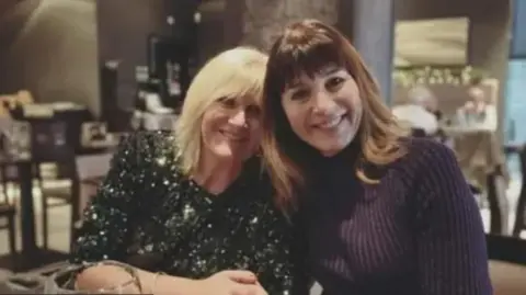 Central Scotland News Agency Two women, one wearing a sparkly green top and the other wearing a purple top, sit closely together in a restaurant