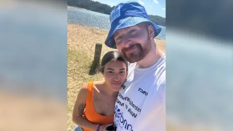 Billy Whiston A selfie of Billy and his girlfriend Lucy stood in front of a beach in the sun.