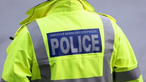 A close up of the back of a police officer's hi-vis jacket with the Greater Manchester Police logo on it.