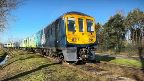 A hydrogen powered train that is coloured both light and dark green with a yellow front