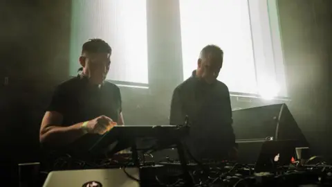 Getty Images DJ duo Slam performing on stage, standing behind their decks