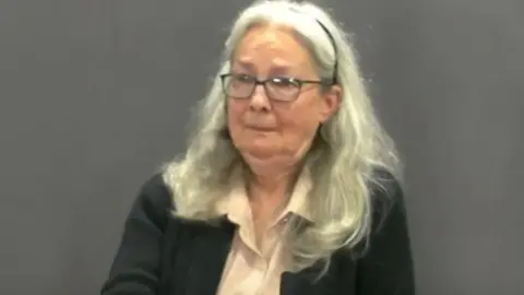 YouTube Jennifer O'Dell with shoulder-length light coloured hair wearing dark framed glasses and a dark cardigan over a light coloured shirt 