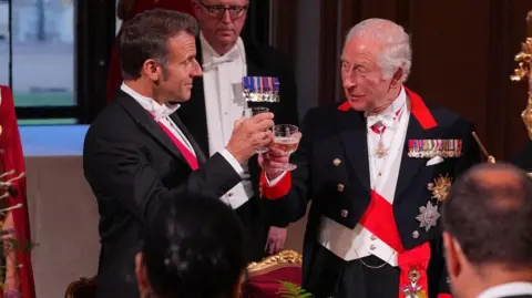 Emmanuel Macron (left) and King Charles clink glasses in a toast
