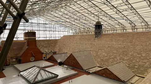 A large tent and scaffolding structure covering the Cornerstone building in Kettering. The images shows the newly laid roof.