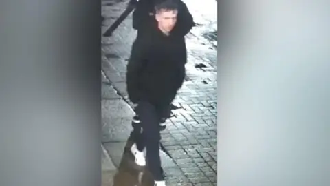 Man wearing white trainers and a black coat