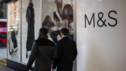 Two men walk past an M&S store