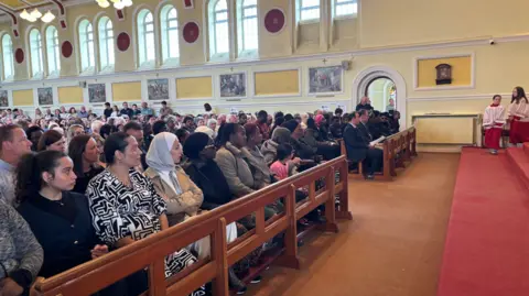 A large crowd sitting in seats inside a church.