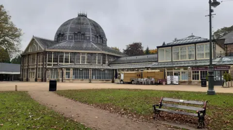A bench in front of a dome structure with grey skies behind