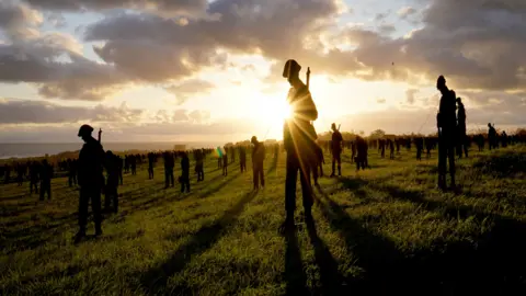 PA Media Silhouette figures and sunset