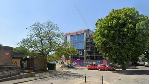 A Google Maps image of the centre in Worthing. There are trees either side and some red cars parked in front of it. 