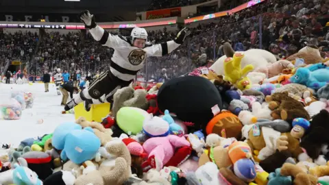 Hershey Bears ice hockey player jumps into pile of stuffed animals on ice rink