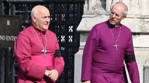 Getty Images Archbishop of York Stephen Geoffrey Cottrell (left) and The Archbishop of Canterbury Justin Welby outside Westminster Hall, London. They are wearing robes and have a cross hanging around each of their necks.
