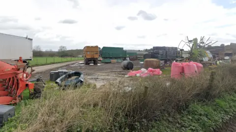 Google Muddy ground in the country side with farm equipment and lorry