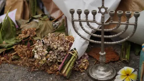 A menorah pictured alongside a wilting bunch of flowers at the Bondi memorial