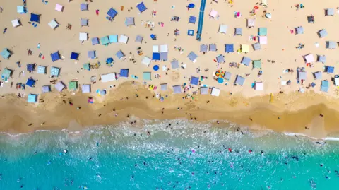 Jordys Drone Photography A drone shot showing cabanas on the sand and swimmers in the water