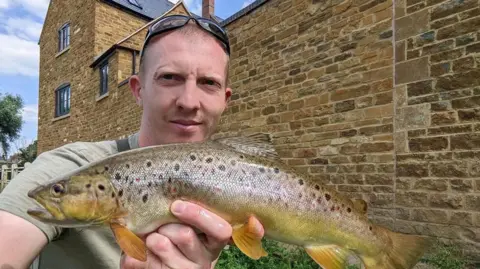 Liam McCarlie holding a fish he has caught.