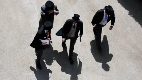 PA Media Aerial view of group of four men wearing top hats and tailcoats