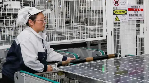 An employee working on the production line of solar panels at a workshop of Trina Solar in China.