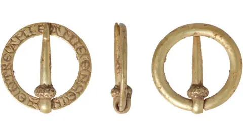 Andrew Williams/Norfolk County Council Three views of 13th or 14th Century brooch, made of a circular band of gold, showing the inscribed back, a side view and the plain curved front, with a pin, attached on one side of the band with a loop and swung across the middle to touch the opposite side of the band.