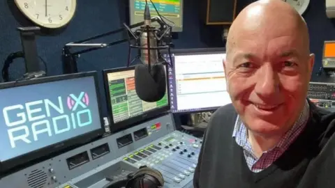 Tim Gough sitting at GenX radio desk