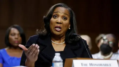 Reuters Woman sits at microphone and speaks