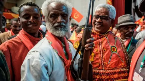 Getty Images An attendee holds a rifle as people dance during the Tigray People's Liberation Front (TPLF) First Emergency General Congress in Mekelle, Ethiopia, on January 4, 2020