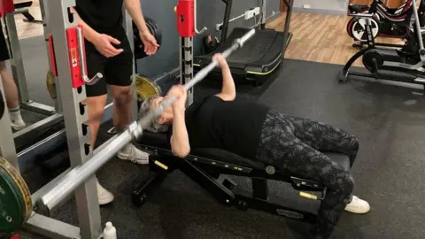 A woman bench pressing a barbell