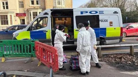 South Yorkshire Police Police in forensic suits next to a police van on a Doncaster street 