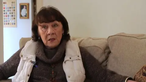 Eileen Jordan sits on her sofa