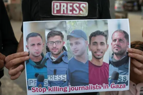 EPA/Shutterstock A poster of journalists Anas al-Sharif, Ibrahim Zaher, Mohammed Noufal, Moamen Aliwa and Mohammed Qreieh being held up in someone's hands.
