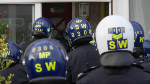 Police in helmets raiding a property in London