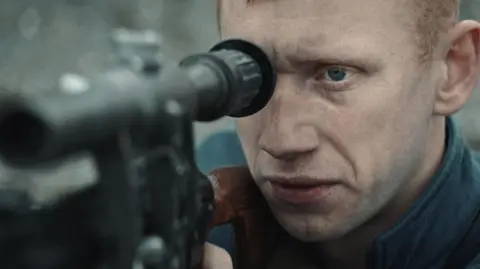 Franz Böhm A still of the film shows a distressed Oleksandr Rudynskyy looking down the sights of a rifle gun