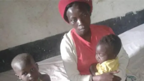 Jokus, Red Cross Joseline and her two kids in a school classroom in Uganda's Kasese district where she has taken refuge after the floods