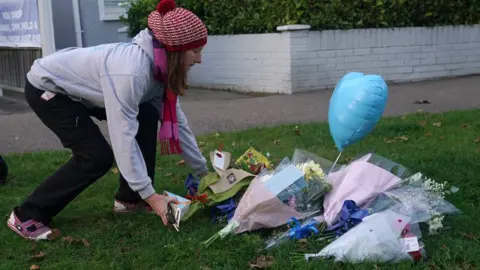 PA Media A woman lays flowers at the scene near the Belfairs Methodist Church in Eastwood Road North, Leigh-on-Sea, Essex