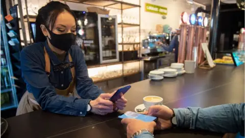 Getty Images Waitress checks a customers Covid cert