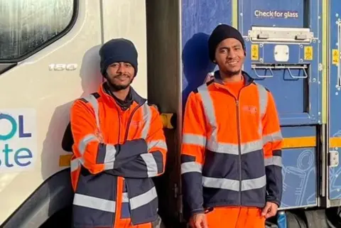 Bristol Waste Two brothers wearing hi-vis jackets and hats stand in front of a bin lorry.