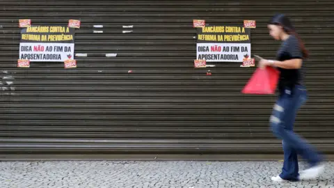 Reuters A woman walks past a bank during a general strike against the government's pension plan in Rio de Janeiro