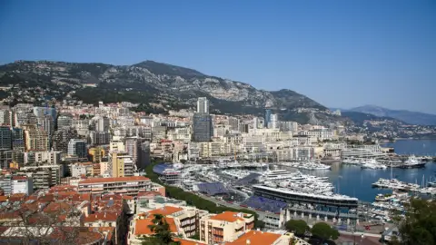 Getty Images Aerial view of Port Hercules, filled with yachts, and the tower blocks of Monte Carlo in Monaco, with mountains rising behind them and Cap Martin visible in the distance