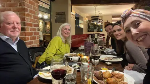Handout A selfie taken during a family dinner. An older couple sit to the left. To the right, Francesca Vincent, who appears to be taking the picture, smiles towards the camera. 
