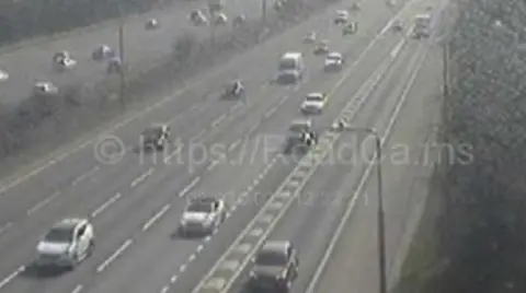 A CCTV camera of a motorway. There are a few cars driving on the road.