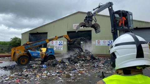 Smoking rubbish being removed from the fire-hit recycling centre