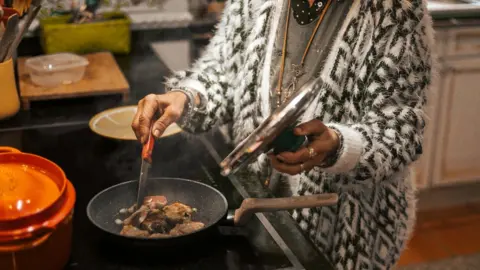 Getty Images Woman cooking on a stove