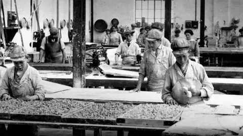 Factory staff are working in a sweet factory in Maidstone in a black and white archive photograph