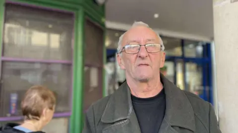 A man stood near the doors of the shopping centre, reminiscing