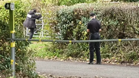 Police officers searching the countryside in Cleeve