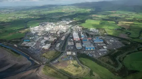 Sellafield Ltd An aerial view of the Sellafield site. Dozens of concrete buildings are surrounded by green fields. In the top right, the sea can be seen.