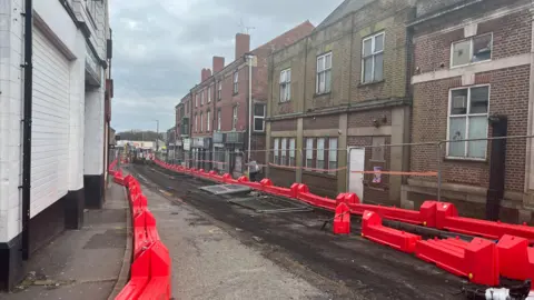 High street with red construction bollards on either side 